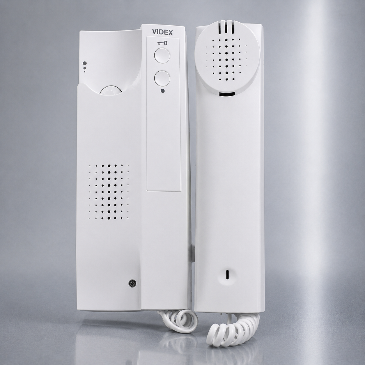 A white VIDEX intercom telephone set with a wall-mounted receiver, speaker handset, and coiled cord on a reflective gray studio background.