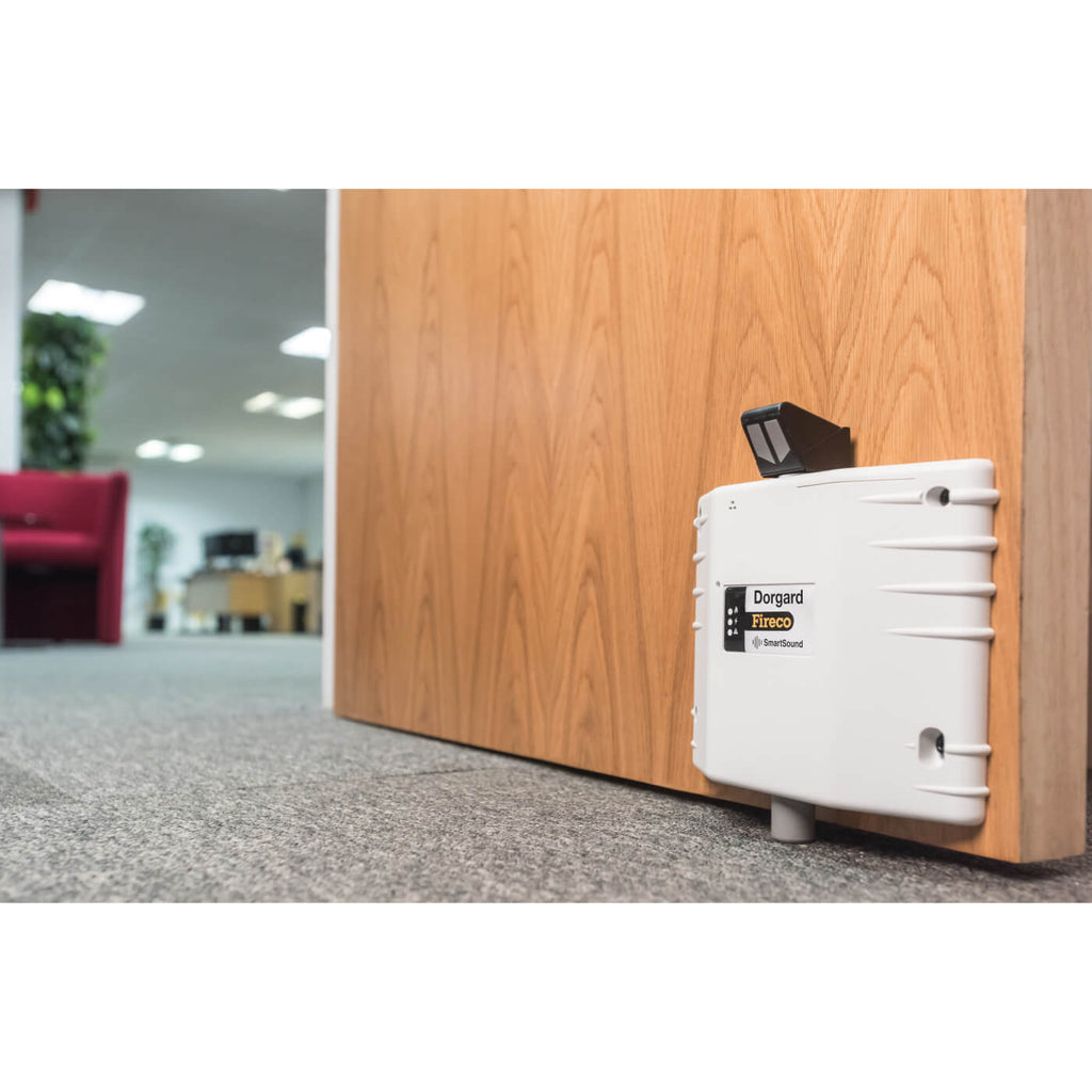 White Fireco Dorgard SmartSound fire door retainer fitted to an office fire door