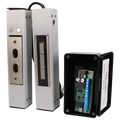 A metal magnetic lock or door stop assembly shown in two upright positions, alongside an open black electrical control box containing a circuit board and terminal strip. ADAMS RITE 1354-0201