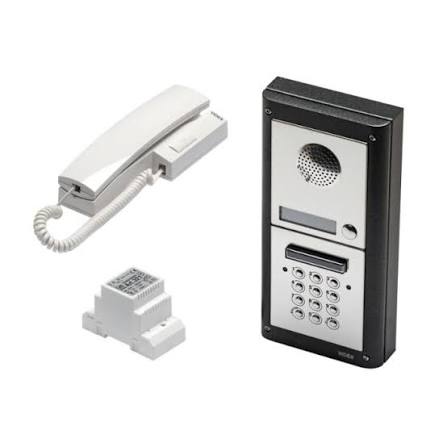 A white and black intercom system set including a wall-mounted panel with a keypad, speaker, and display, a corded handset, and a small white connector block, shown on a plain white background.